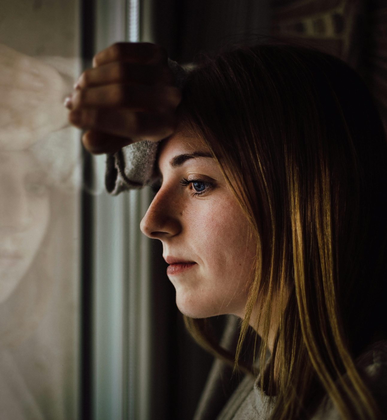 woman leans onto a glass window looking out