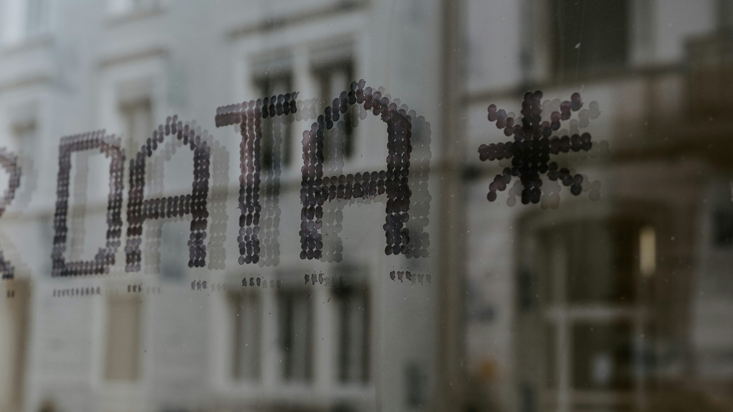 Window reflecting a building with the word Data on the window